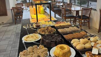 Disposição de buffet com diversos alimentos e um smartphone no balcão.