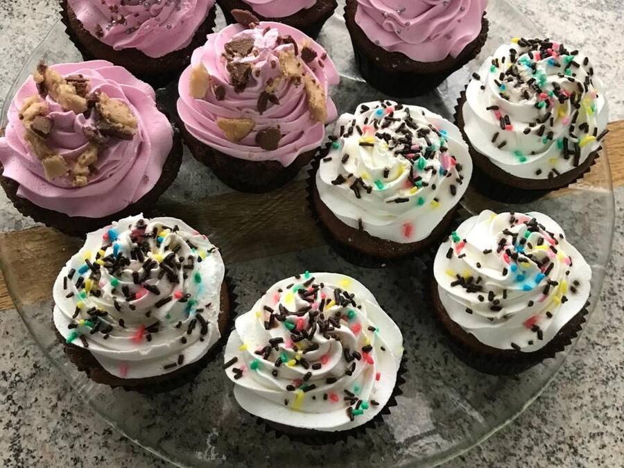 A glass plate with six cupcakes, each with different frosting and toppings.