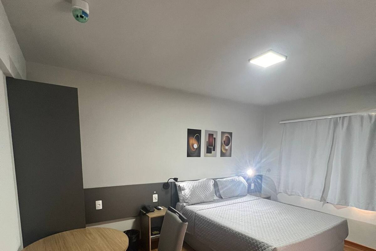 A hotel room with a bed, a desk, a chair, and a small table.