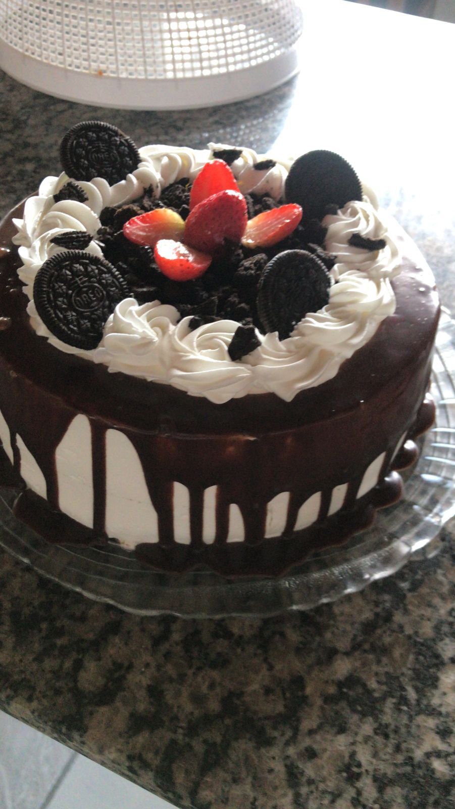 A cake with white frosting, chocolate drizzle, and chocolate chips.