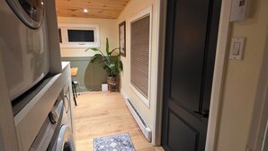 Un espace buanderie comprenant un lave-linge, un plafond en bois, une porte et un tapis à motifs.
