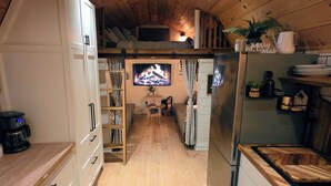 Une cuisine chaleureuse avec des meubles en bois, un four encastré et un téléviseur.