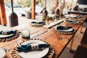 A wooden table set with plates, napkins, and candles, suggesting a dining area.