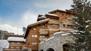 Un edificio de madera de varios pisos con arcos de piedra y balcones, rodeado de nieve.