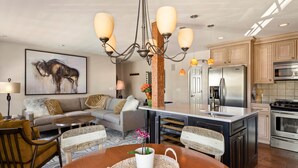 A modern kitchen with a central island, built-in appliances, and a dining area with a round table and chairs. - Cozy Condo in Snowmass Village (Snowmass Village)