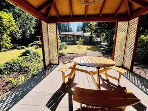 A wooden gazebo with a table and chairs, surrounded by a garden with a lawn and trees. - Charming 2BR w/ Garden Retreat & 2 Free Parking (Bothell)