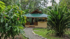 A small, single-story building with a green roof, surrounded by lush greenery. - Chiquita Casitas - Macaw & Toucan - Coastal Caribbean Comfort (Playa Chiquita)