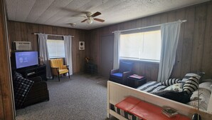 Ein Zimmer mit einem Bett, einem Schreibtisch mit Computer, einem Stuhl und einem Fernseher.