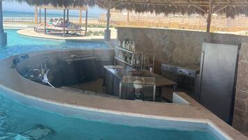 A poolside bar area with a thatched roof, a hot tub, and a bar counter.