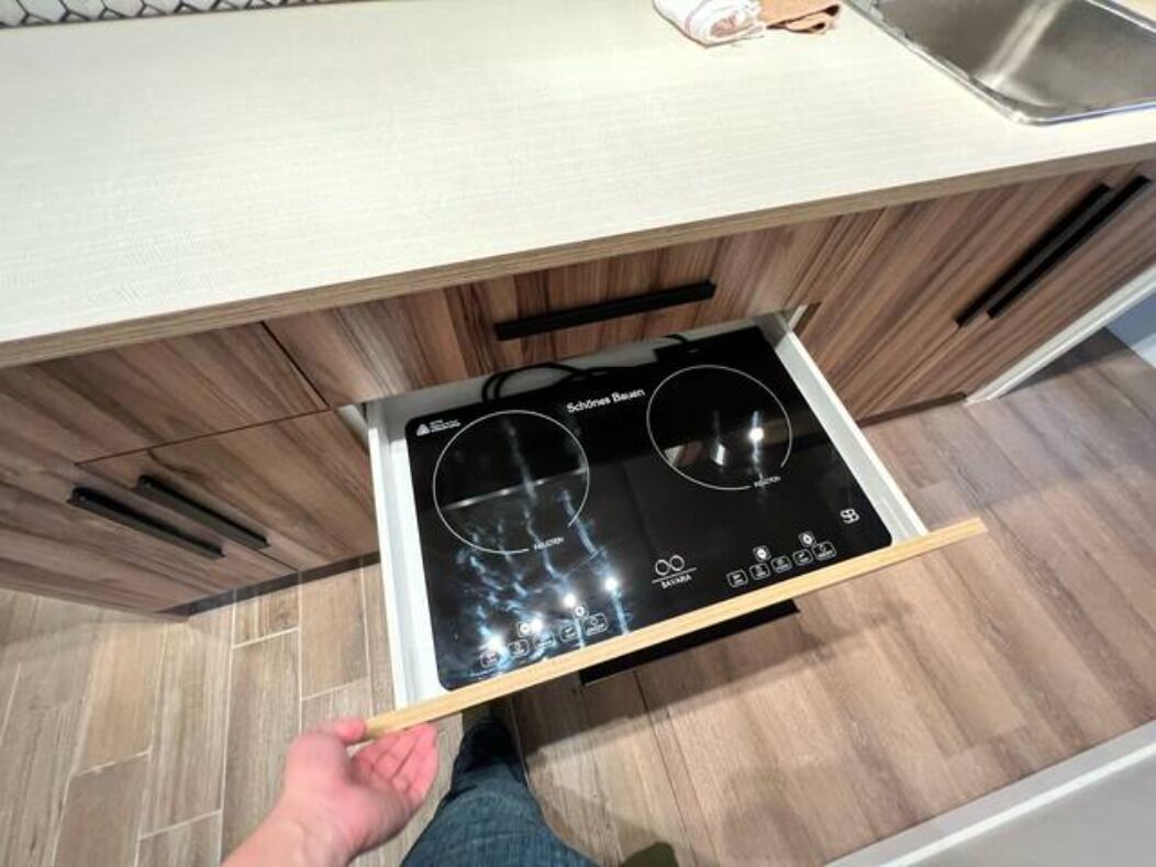 A kitchen with a built-in stove and a drawer with a handle.