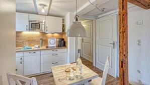 A compact kitchen with white cabinets, a wooden countertop, and a hanging pendant light.