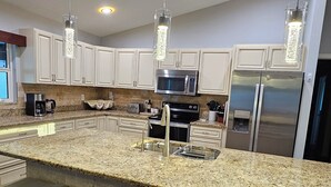 A modern kitchen with a large island, stainless steel appliances, and pendant lighting. - Very Clean, Peaceful 3-bedroom house in tranquil North Port with AC, WiFi (North Port)