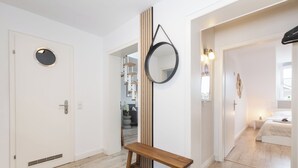 A modern interior with a wooden bench, a round mirror, and a white door with a circular window. - Mc´maggies Atelier mit Insgesamt 6 Schlafplätzen (Meerbusch)