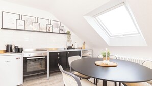 A modern kitchen with a dining area, featuring a Bosch refrigerator, a built-in oven, a black dining table with four chairs, and a skylight above. - Mc´maggies Atelier mit Insgesamt 6 Schlafplätzen (Meerbusch)