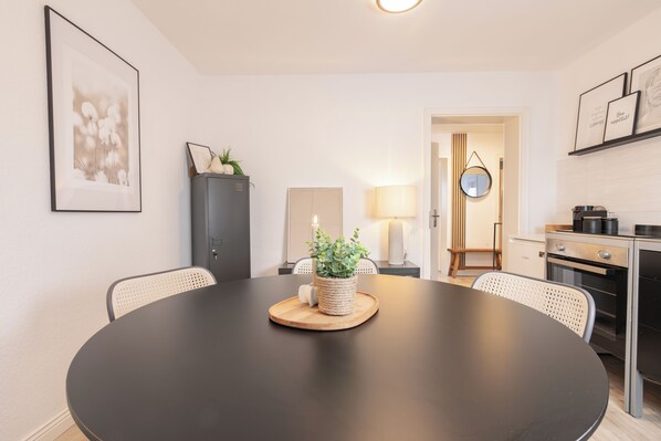 A modern kitchen with a round dining table, chairs, a cabinet, a lamp, and a mirror.