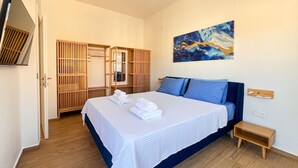 A bedroom with a bed, a wooden wardrobe, a painting, and a small wooden table. - Sapphire Zafeirenias Gem House With Jacuzzi (Hersonissos)
