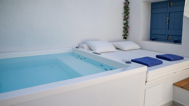 A modern spa room with a large bathtub, white walls, and a window with blue shutters. - Sapphire Zafeirenias Gem House With Jacuzzi (Hersonissos)