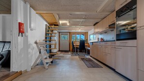 Una cocina moderna con armarios de madera, horno empotrado y comedor con mesa y sillas.