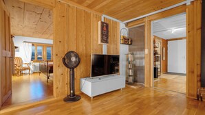 Un interior de madera con televisor, ventilador y estanterías.