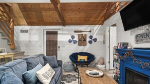 A cozy living room with a blue couch, a wooden coffee table, and a blue fireplace.