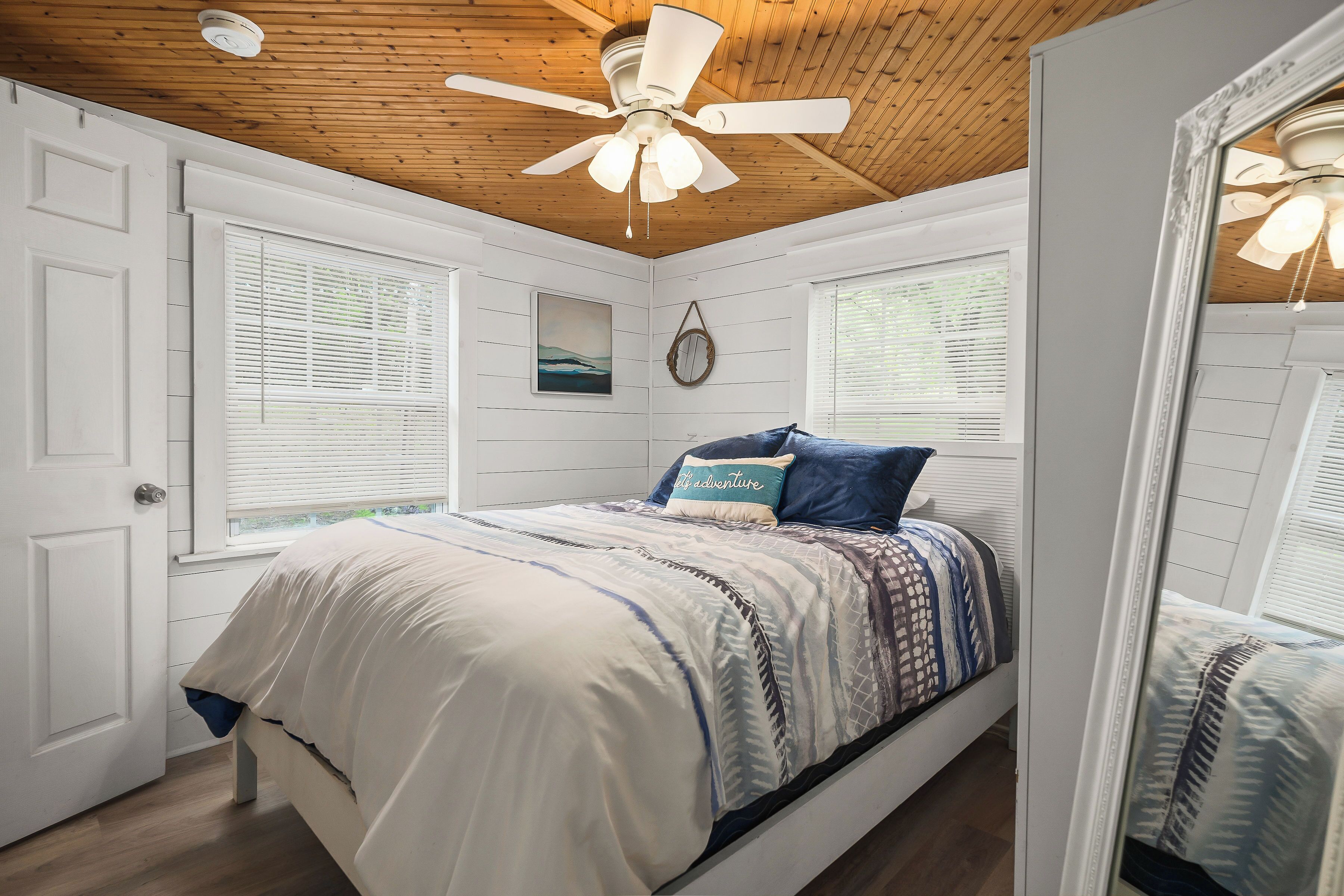 A bedroom with a bed, a ceiling fan, and a window with blinds.