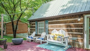 A log cabin with a porch, outdoor seating, and a fire pit.