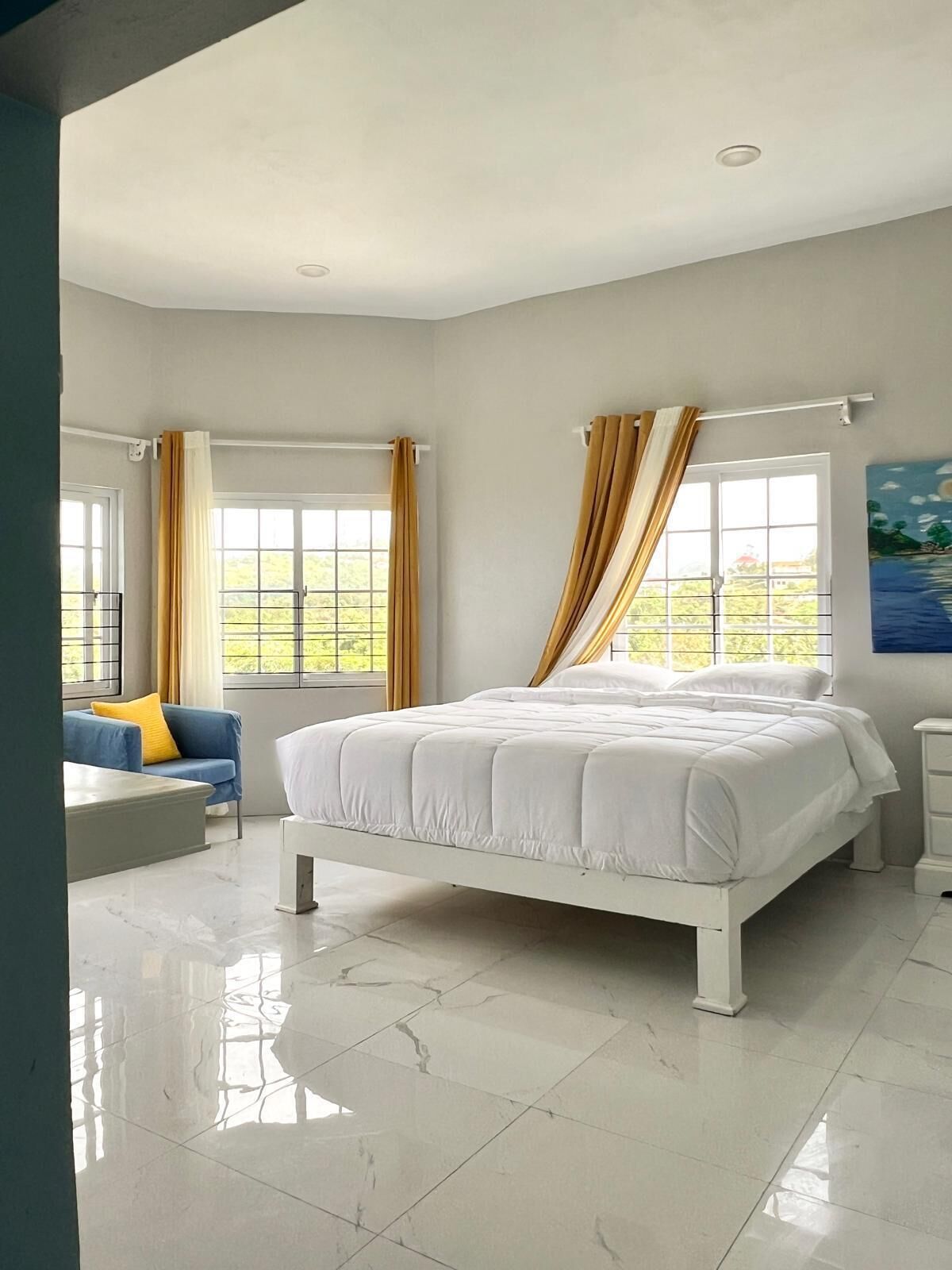 A bedroom with a bed, a sofa, and a painting on the wall.
