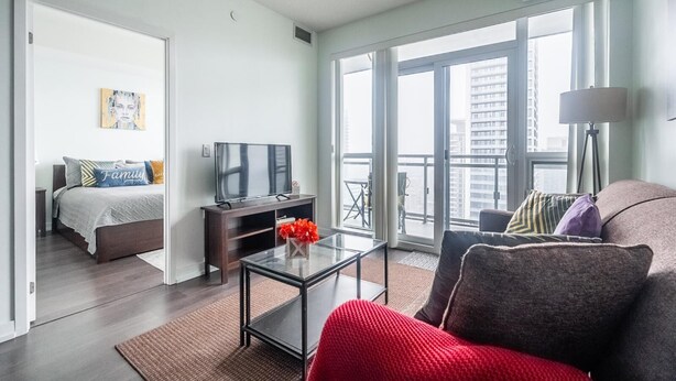 Un salon moderne comprenant un canapé, une table basse, un téléviseur et un balcon offrant une vue sur la ville.