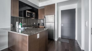 Une cuisine moderne avec des meubles de couleur bois foncé, un réfrigérateur en acier inoxydable et un plan de travail en granit.