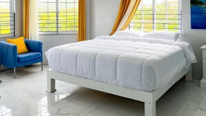A bedroom with a bed, a chair, and a window with curtains.