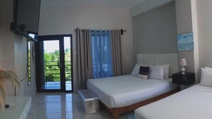 A hotel room with a large bed, a bench, a bedside table, and a view of greenery through a glass door.