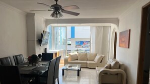 A compact living space with a dining area, a sofa, a coffee table, and a ceiling fan.