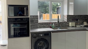 Una cocina moderna con electrodomésticos integrados, lavadora y ventana con vistas al exterior.
