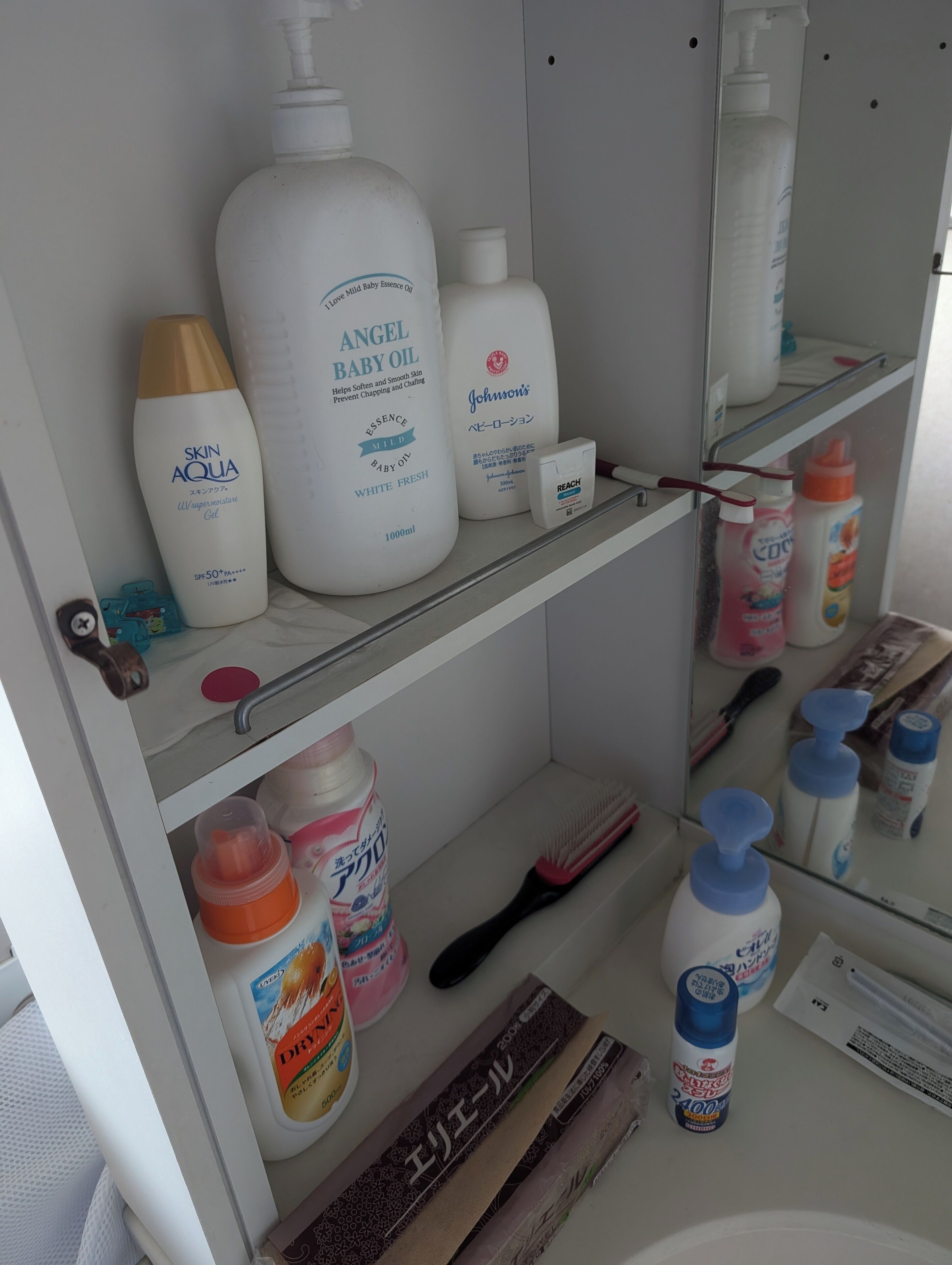 Baño con repisas que contienen varios artículos de tocador, como aceite para bebé, loción para bebé y otros productos de cuidado personal.