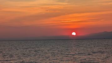 A sunset over a calm sea with a distant mountain range.