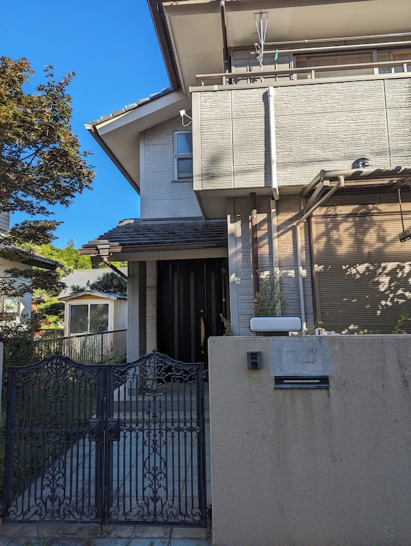 Un edificio residencial con entrada porticada, puerta de garaje y una ventana pequeña.