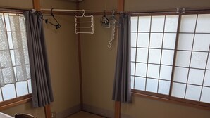 Habitació amb tatami, escriptori de fusta, cadira i una estant per a roba penjada.