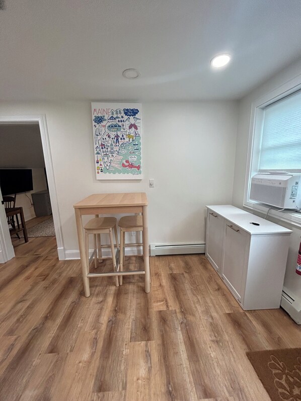 A kitchen with a white refrigerator, a microwave, and a small table with two stools.