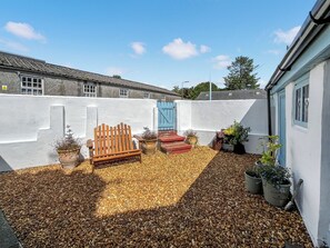 A courtyard with a wooden bench, potted plants, and a blue gate.