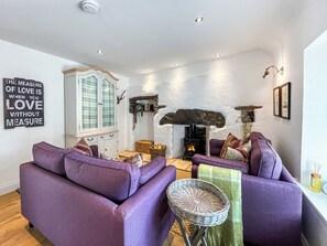 A living room with purple sofas, a stone fireplace, and a cabinet with glass doors.