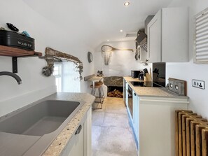 A kitchen with a granite countertop, a sink, a stove, and a refrigerator.
