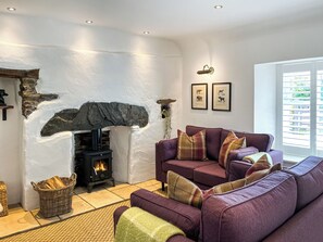 A living room with a stone fireplace, a purple sofa, and a wicker basket.