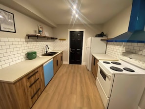 A kitchen with white tiled backsplash, wooden cabinets, a dishwasher, a stove, and a black door. - Newly Renovated 1br1ba With Asian Style (Edmonton)