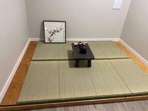 A tatami mat room with a small table, a framed artwork, and a traditional tea set. - Newly Renovated 1br1ba With Asian Style (Edmonton)