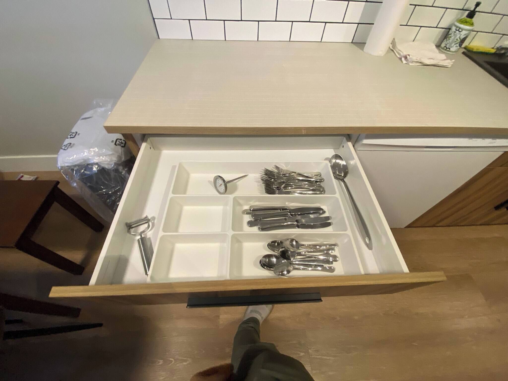 A drawer with utensils and a spoon.