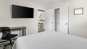 A bedroom with a bed, a desk, a chair, a ceiling fan, and a TV. - Entire Home - Great Location (Charleston)