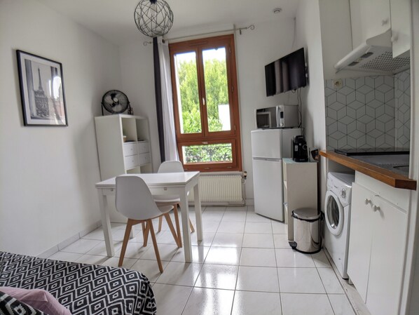 A compact kitchen with a dining area, a washing machine, and a microwave.