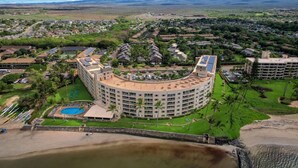 A large, circular hotel with multiple floors, a swimming pool, and a beach area. - Beautifully Upgraded, Amazing Ocean Views MS316 (Kihei)