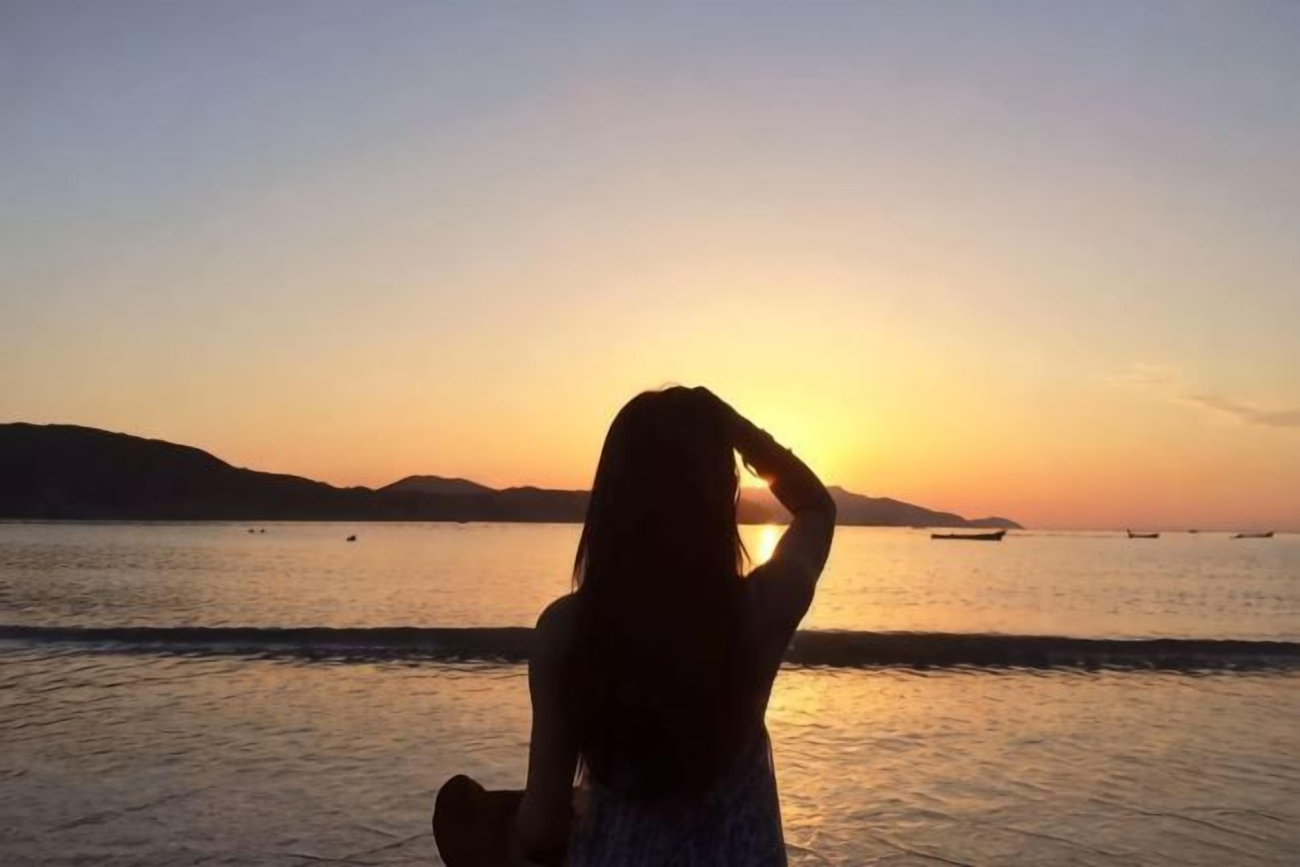A silhouette of a person at sunset by the water.