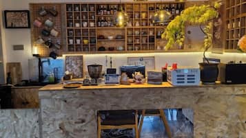 Una zona de bar con mostrador de piedra, estanterías con botellas y una planta colgante.